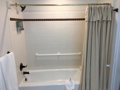 a bathroom with a tub and a shower curtain at Lake Pointe Inn in McHenry