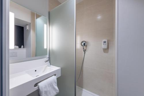 y baño con ducha, lavabo y espejo. en B&B HOTEL Paris Meudon Vélizy en Meudon