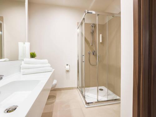 a bathroom with a glass shower and a sink at VacationClub - Baltic Park Molo Apartament C304 in Świnoujście