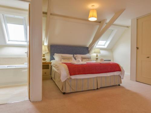 a bedroom with a large bed with a red blanket at St Aubyn Cottage in Plymouth