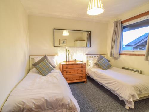 a bedroom with two beds and a dresser and a mirror at Kestrel Lodge in Beeswing