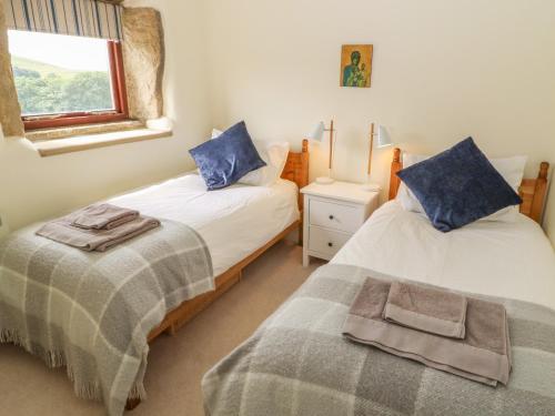 two twin beds in a room with a window at 1 Horsehold Cottage in Hebden Bridge