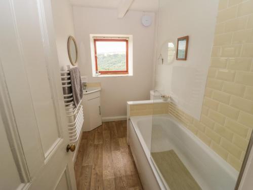 a white bathroom with a tub and a sink at 1 Horsehold Cottage in Hebden Bridge