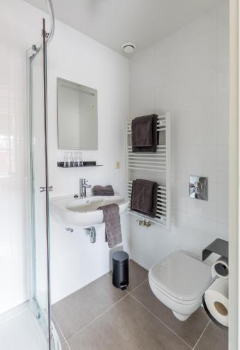a white bathroom with a toilet and a sink at Logement de Spaerpot in Middelburg