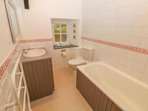 a bathroom with a tub and a toilet and a sink at Churchgate Cottage in Bodmin