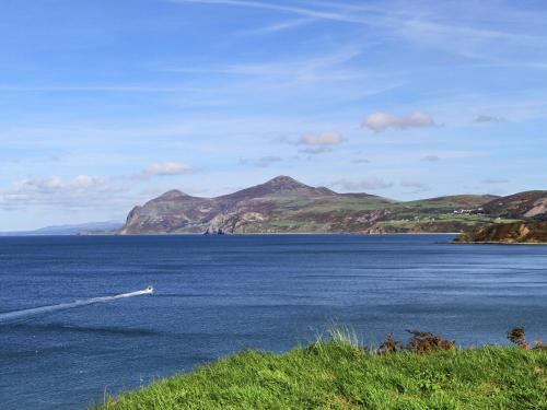 a boat in a large body of water with mountains at Bwthyn Bach in Nefyn