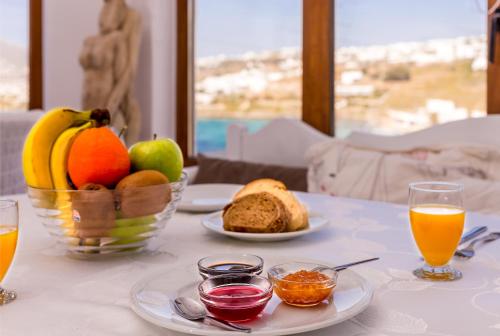 a table topped with a plate of fruit and a glass of orange juice at Cape Mykonos in Mikonos