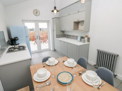 a kitchen and dining room with a wooden table and chairs at Coeden Bach in Burry Port