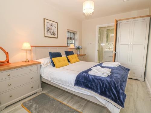 a bedroom with a bed with blue and yellow pillows at Holly Cottage in Criccieth