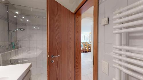 Un baño con ducha y puerta de madera. en Splendura 2A, en Silvaplana