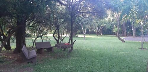 a park with two benches and a grill in the grass at Suikerbosrant Sleep and go in Pretoria