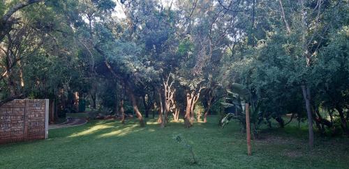 a yard with trees and grass with a fence at Suikerbosrant Sleep and go in Pretoria