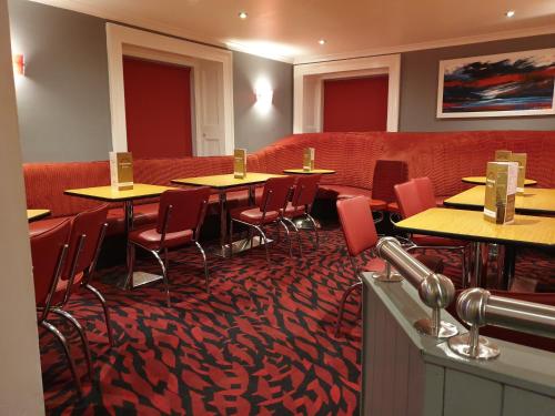 a restaurant with tables and chairs and a red couch at Commercial Hotel in Alness