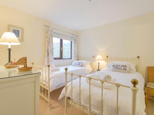 a bedroom with a white bed and a window at 12 Burgh Island Causeway in Kingsbridge