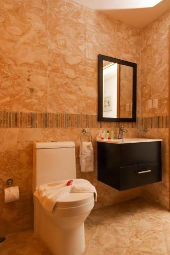 a bathroom with a toilet and a sink and a mirror at Sybaris Suites & Residences in Juan Dolio