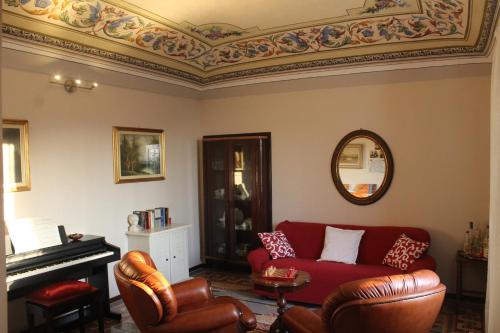 a living room with a red couch and a piano at La Terrazza sul Monferrato in Ozzano Monferrato