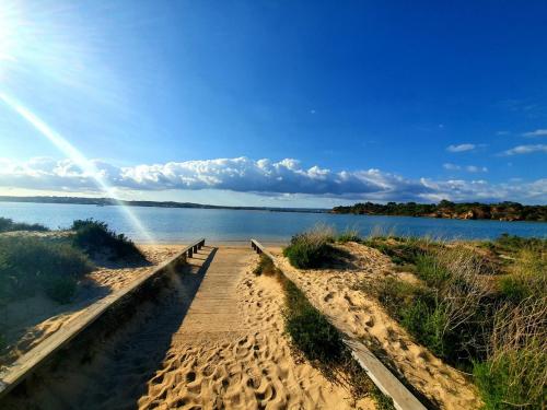 a boardwalk on a beach next to a body of water at AlvorMar Apartamentos Turisticos in Alvor