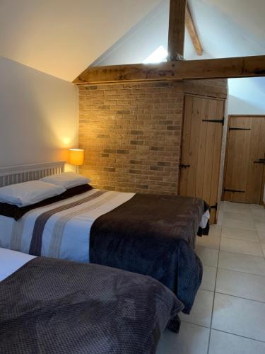 a bedroom with two beds and a brick wall at Appletree Cottages in Mildenhall