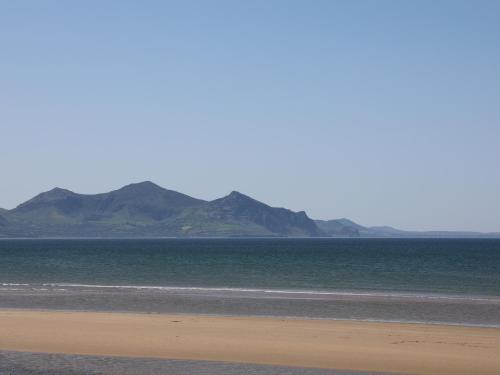 a beach with mountains in the background and the ocean at Sea Breeze in Caernarfon