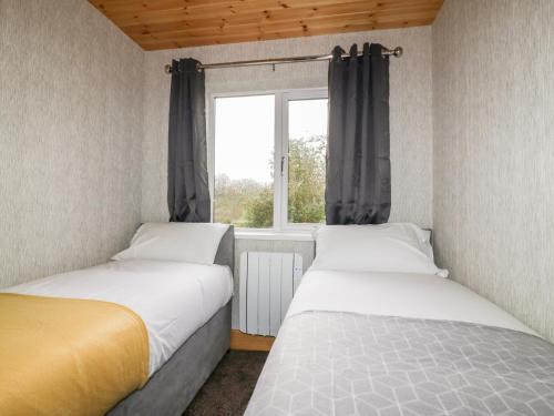 Lodge Two في ترورو: سريرين في غرفة صغيرة مع نافذة