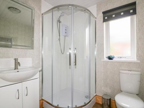 a bathroom with a shower and a sink and a toilet at Lodge Three in Truro