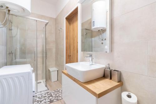 a white bathroom with a sink and a shower at Apartments Fiorello in Rijeka