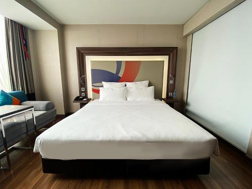 a bedroom with a large white bed and a chair at Novotel Bangkok IMPACT in Nonthaburi