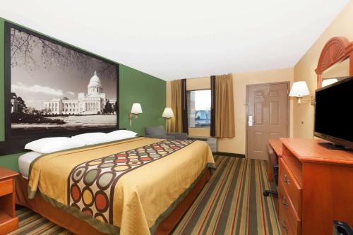 a hotel room with a large bed and a flat screen tv at Super 8 by Wyndham Jacksonville AR in Jacksonville