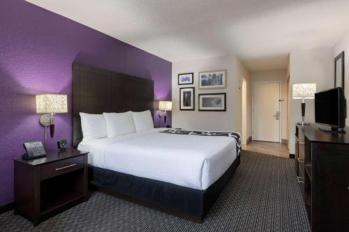 a hotel room with a large bed and purple walls at La Quinta by Wyndham Clifton/Rutherford in Clifton