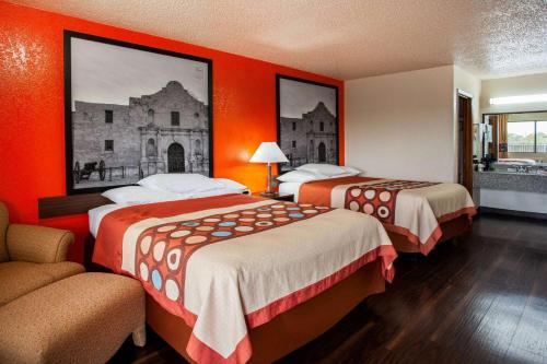 a hotel room with two beds with orange walls at Super 8 by Wyndham Giddings in Giddings