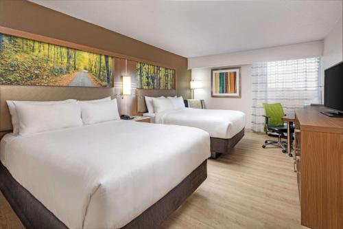 a hotel room with two beds and a desk at Wyndham Garden Marietta Atlanta North in Marietta