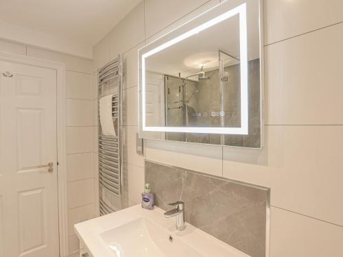 a white bathroom with a sink and a mirror at 7 Thurlestone Rock in Kingsbridge