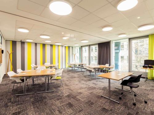 a conference room with tables and chairs and windows at Novotel Düsseldorf City West in Düsseldorf