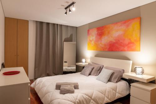 ein Schlafzimmer mit einem weißen Bett und einem Gemälde an der Wand in der Unterkunft Porto Dragão in Porto