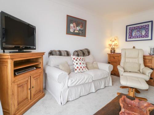 a living room with a white couch and a flat screen tv at 14 Lyme Mews in Seaton