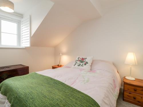 a bedroom with a bed with a green blanket at 14 Lyme Mews in Seaton