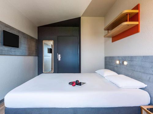 a large white bed with a pair of scissors on it at ibis budget Paris Porte d'Italie Ouest in Le Kremlin-Bicêtre