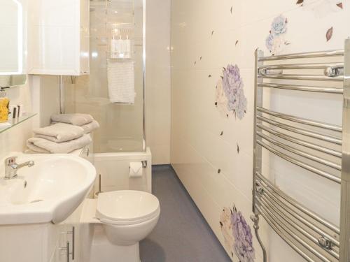 a white bathroom with a toilet and a sink at Llys Madoc, First Floor Flat in Penmaen-mawr