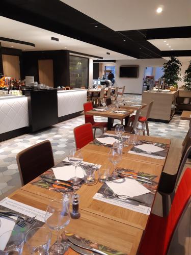 a restaurant with wooden tables and chairs with wine glasses at Campanile Chartres in Chartres