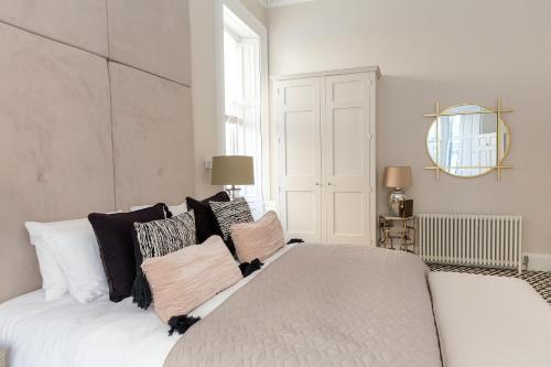 um quarto com uma grande cama branca com almofadas em The Lane Hotel em Edimburgo