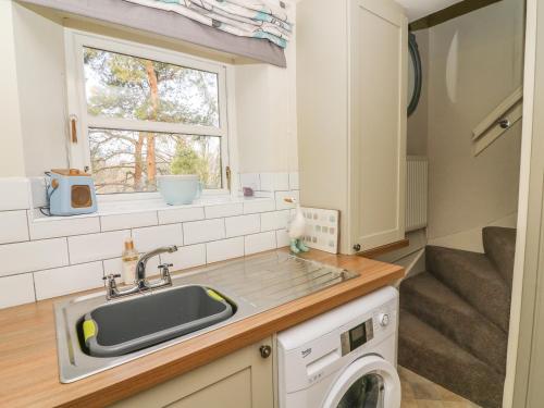 una cucina con lavandino e lavatrice di Bank End Cottage a Carnforth