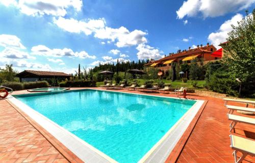 una gran piscina con sillas y una casa en Calanchi Apartments, en Montaione