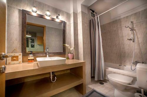 a bathroom with a sink and a toilet and a mirror at Marina View Luxury Home in Gouvia