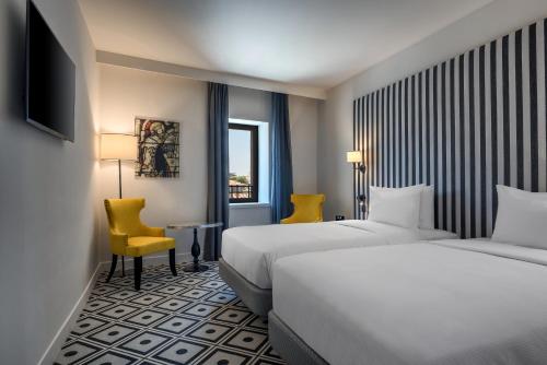 a hotel room with two beds and a table and chairs at Hotel du Roi & Spa by SOWELL COLLECTION in Carcassonne