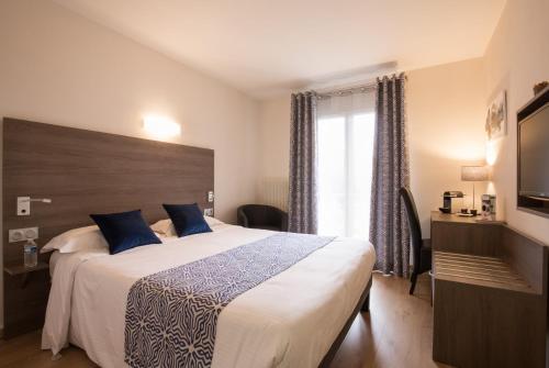Habitación de hotel con cama grande y ventana en Logis Hotel Le Petit Casset, en La Boisse