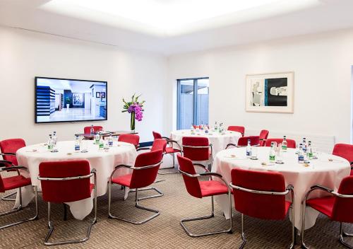 a room with white tables and red chairs at The Croke Park Hotel in Dublin