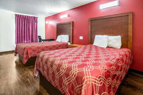 Econo Lodge Knoxville في نوكسفيل: غرفة فندقية بسريرين وجدار احمر