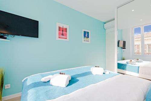 a blue bedroom with two beds and a flat screen tv at L'Albion YourHostHelper in Cannes