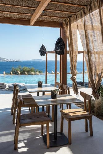 a dining room with tables and chairs and a view of the ocean at Rocabella Mykonos Hotel in Agios Stefanos