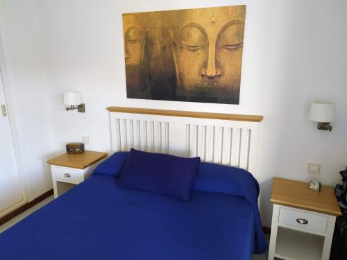 塔烏里托的住宿－Ocean view apartment in Taurito, Mogan - Top Floor，卧室配有蓝色的床和墙上的绘画作品